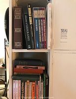 Bookshelf with assorted cookbooks, home improvement books, and Tony Robbins CDs with visible titles such as Chess, Advanced Geography, Food Microbes, Kitchen Repairs & Solutions, Home & Holiday Traditions.
