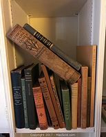 Shelf of vintage books with focus on Theodore Roosevelt's African Game Trails and Lewis Carroll's Alice's Adventures in Wonderland.