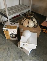 Overview photo showing boxed light fixtures and vintage hanging light on cardboard box.