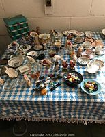 Wide view of collection on table showing salt and pepper shakers, ceramic and glass items, demitasse cups and saucers, and finger bowls.
