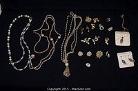 Full view of lot showing multiple pearl necklaces, earrings, and loose pieces arranged on black background.