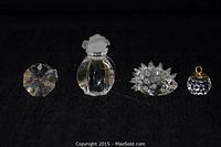 Four Swarovski crystal items displayed on black cloth including porcupine, kugel ornament, oyster with pearl, and rose top paperweight