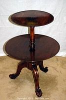 Front view of the antique walnut two-tiered table showing both circular tabletops and turned central column.