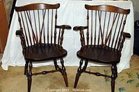 Pair of dark stained Vermont pine armchairs shown side by side with wooden spindle backs, curved top rails, and contoured wooden seats