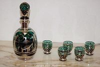 Full set includes decanter with stopper and five matching glasses on marble surface.