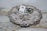 Angled view of the antique Meridien plated centrepiece plate showing ornate floral edging, embossed central floral medallion, and reflective surface.