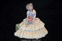 Front view of seated female figure in pastel dress and bonnet.