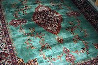 Full view of rug showing green field with central medallion and floral motifs