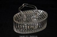 Front angled view of a clear lucite purse with vertical ribbing and a single handle, shown closed with clasp.
