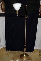 Full view of the adjustable silver plated floor lamp with white milk glass shade against a dark background.