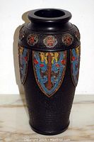 Front and side view of textured black vase with colorful floral relief patterns around upper part