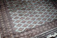 Angled view showing grey ground, repeating rose medallion motifs, and decorative border