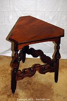 Full side view of the walnut triangular side table showing turned legs and ornate stretcher supports.