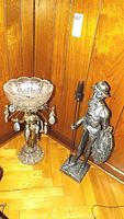 Bronze figural centerpiece with crystal bowl and Don Quixote figure side by side against wood paneling