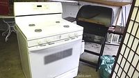 White stove positioned next to black grill in garage space