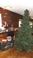 Full view of artificial tree standing next to boxed train set and other decor
