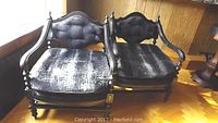 Pair of vintage black painted solid wood armchairs with padded upholstered seats and backs, showing wear and minor paint loss.