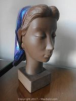 Front view of the ceramic head figurine on a wooden surface