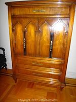 Front view of the fruitwood highboy showing three front doors with gothic arch trim and decorative inlays, plus one drawer above and two drawers below with brass handles.