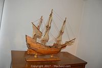 Front-side view of the three-mast wooden model ship sitting on a wooden base, showcasing the sails, rigging, and hull detail.