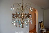 Full view of hanging bronze tone ceiling lamp with four bulbs and glass drops.
