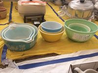 Nine bowls and casseroles displayed, six Pyrex and three Fireking, showing variety of colors and patterns