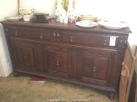 Full view of the dark wood carved buffet showing two drawers atop three cabinets, decorative handles, and surface items (dishes) not included.