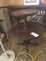 Photo of the full wooden two-tier side table showing the round top and bottom tiers and carved central support, with visible scratches and wear.