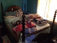 Full view of four poster wooden bed set up with bedding showing the turned posts and size.