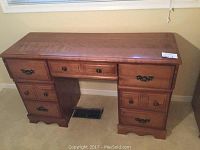 Front view of wooden desk showing top surface and drawer layout with minor wear.