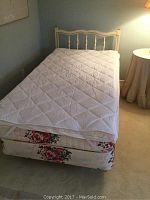 Full assembled bed with quilted mattress pad, mattress and box spring showing floral pattern