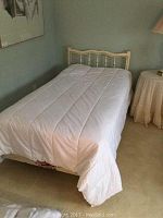 Single bed made with white quilted duvet showing full bedding coverage on single bed frame.