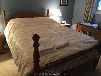 Cream-colored queen size duvet spread on a wooden bed frame in bedroom setting, showing full coverage and condition.