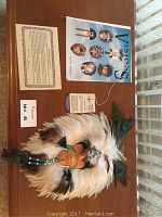 Top view of the shaman mask with certificate, fact sheet, and poem spread on a table.