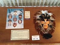 Shaman medicine mask with certificate of authenticity, fact sheet, and booklet arranged on wood surface