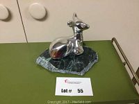 Front angled view of the aluminum fawn sculpture on dark green stone base.