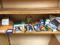 The full shelf view of assorted office supplies including pens, markers, envelopes, and packaged products