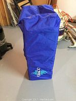 Graco blue carrying bag standing upright in a storage area, featuring the Graco logo in white and green.