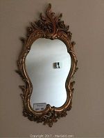 Front view of the ornate gold/copper tone hanging mirror showing the intricate detailing on the frame.