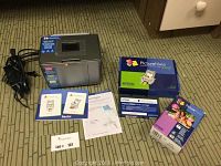 Overview of Epson PictureMate printer with related boxes and manuals on floor