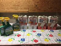 Photo showing cans of Thompson's WaterSeal arranged on a table with three bottles of Weed Out weed killer sprays.