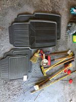 Overview showing the variety of floor mats with two tread patterns, snow brushes, broom, auto flood light and reflectors visible on concrete floor.