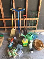 Full view of gardening tools, gloves, twine, watering can, baskets, and plant supports
