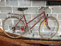 Side view of the red Rossignol Expression 10 speed bike showing full frame, wheels, saddle, and rear rack.