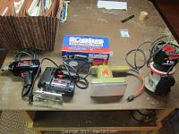 Full view of five power tools on a table including drill, saber saw, sander, router, and boxed condensate pump.