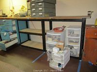 Shelf units made from black metal frames and pressed board shelves in a basement setting, some with items stored, showing removable tops on two units.