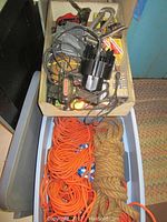 Storage bin containing assorted hand tools including power drill, clamps, black distributor cap and miscellaneous hardware