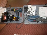 Photo showing Ryobi 14.4V cordless drill-driver, charger, and battery with manuals inside plastic case.