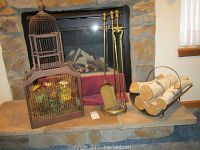 Photo showing all items together: decorative birdcage, fireplace tool set with stand, metal firewood holder with birch logs.