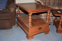 Wooden end table side view showing the turned spindle legs, lower shelf, and closed drawer.